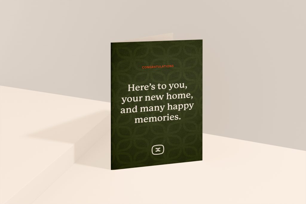 A greetings card stood on a surface saying here's to you, your new home, and many happy memories