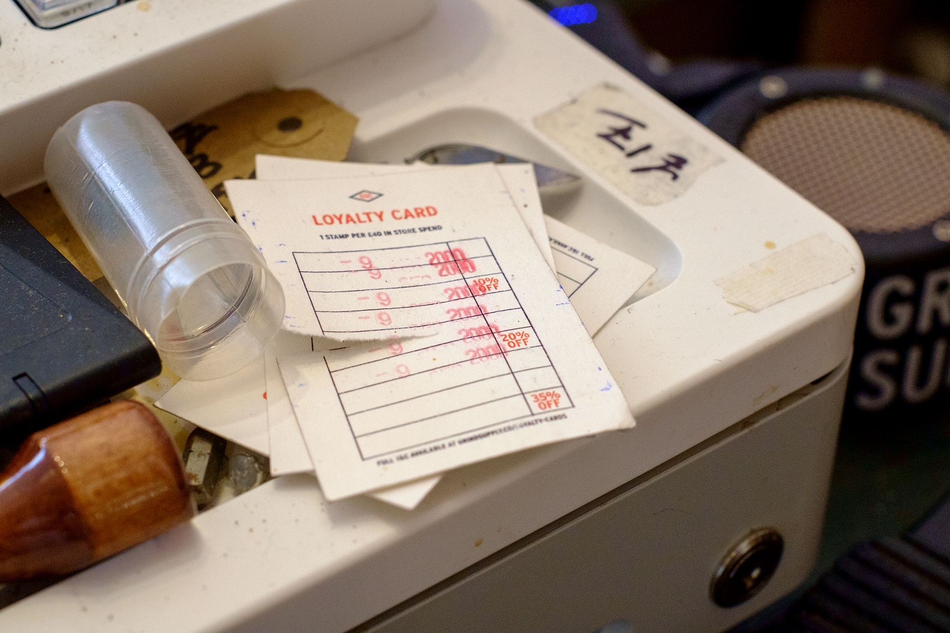 a used loyalty card on top of a pretty messy cash register